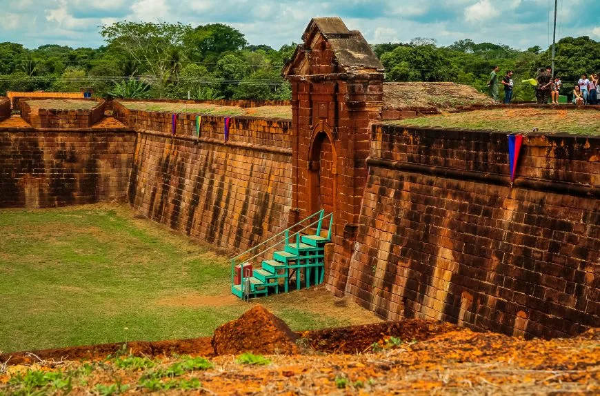 Estruturas remanescentes do Forte Príncipe da Beira, com muralhas de pedra e áreas verdes ao redor.