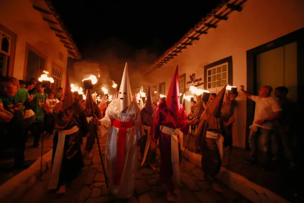 Participantes vestidos com trajes tradicionais carregando tochas durante a Procissão do Fogaréu nas ruas históricas da Cidade de Goiás.