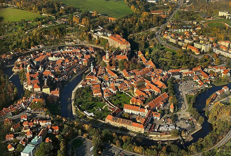 Vista ampla da cidade de Český Krumlov, com o rio Moldava serpenteando entre casas históricas.