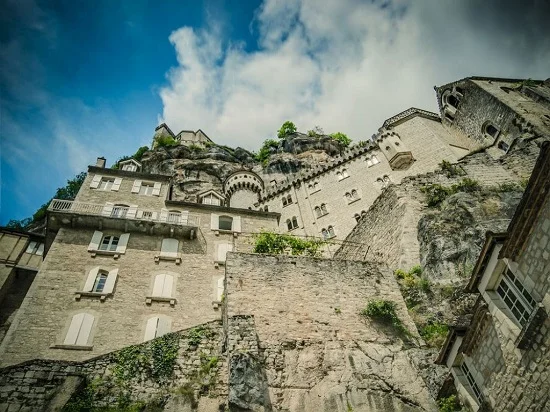 Vista de Rocamadour construída na encosta de um penhasco, evidenciando a fusão entre arquitetura e natureza.