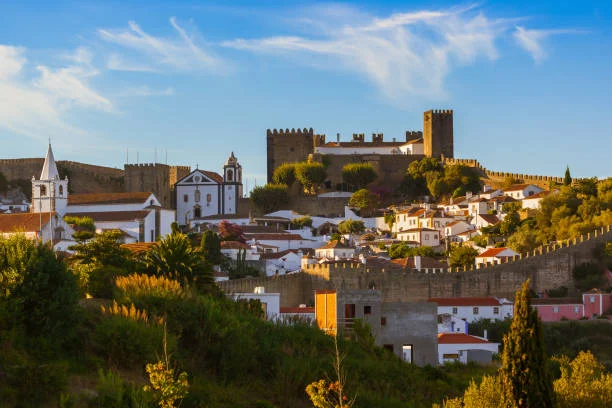 Vista panorâmica das muralhas e do casario branco de Óbidos, destacando a atmosfera medieval da vila portuguesa.
